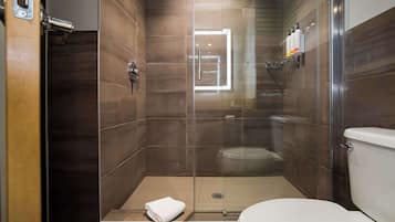 Un baño moderno con ducha de vidrio, inodoro y perchero para toallas.