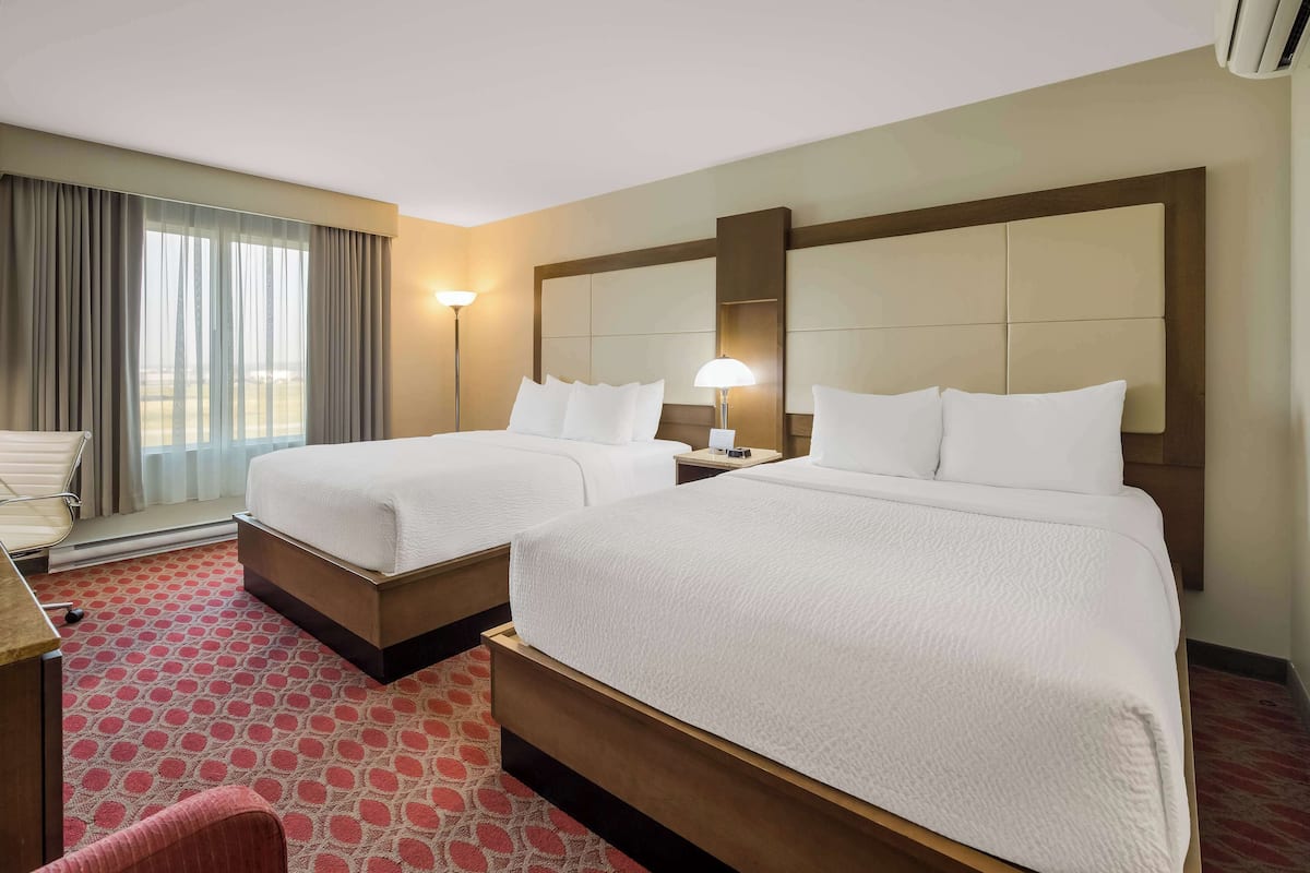 Habitación de hotel con dos camas, un escritorio y una silla.