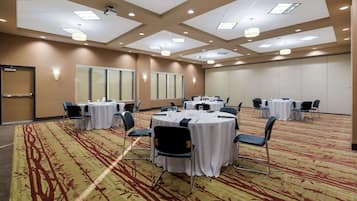 A conference room with round tables, chairs, and a carpeted floor.