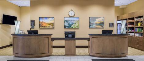 A reception area with two wooden reception desks, a clock, and three landscape paintings on the wall.