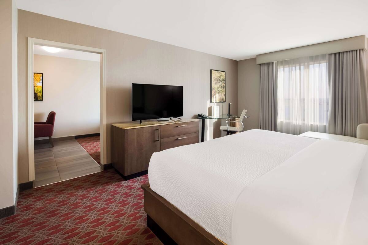 Habitación de hotel con una cama grande, televisión, escritorio y una silla.