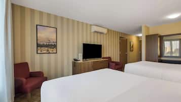 Habitación de hotel con dos camas, televisión, escritorio con teléfono y un cuadro en la pared.