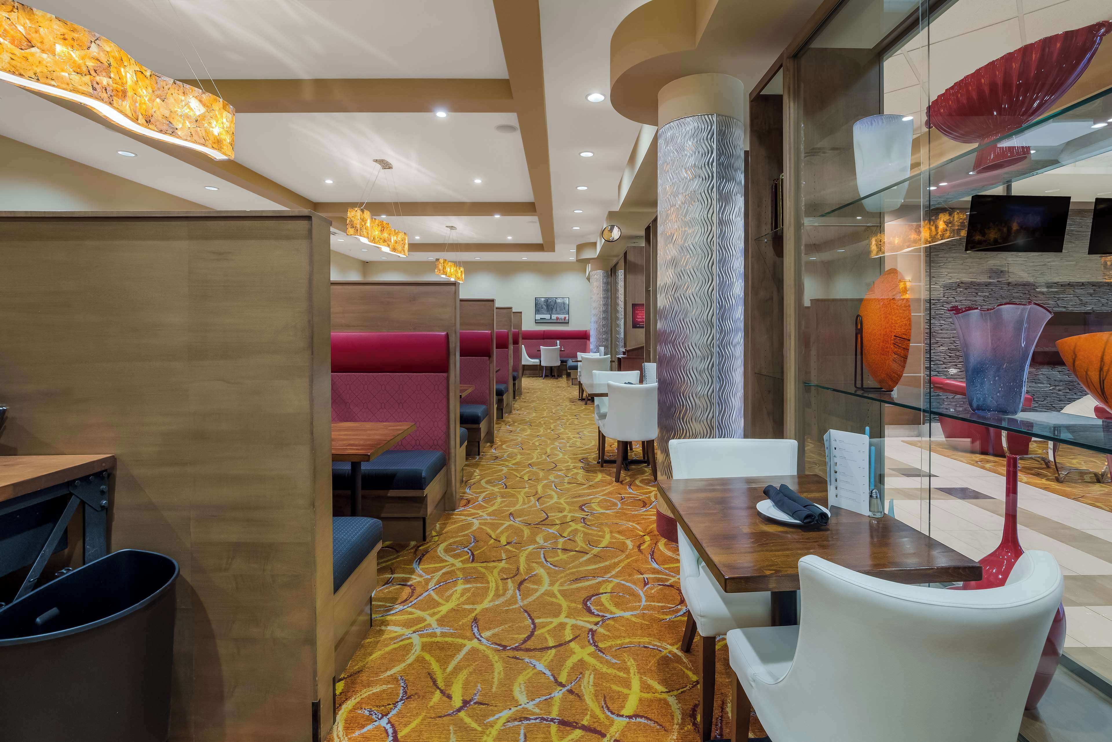A hotel lobby with a patterned carpet, seating areas, and a glass display case with decorative items.