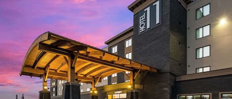 A hotel entrance with a covered lobby area, a visible entrance, and a parking lot.