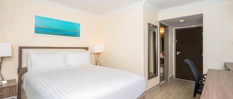Habitación de hotel con una cama grande, lámparas de noche, un escritorio y una puerta que da al baño.