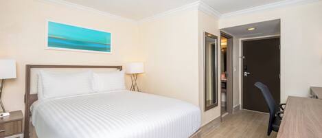 A hotel room with a large bed, bedside tables, a desk, and a door leading to a bathroom.