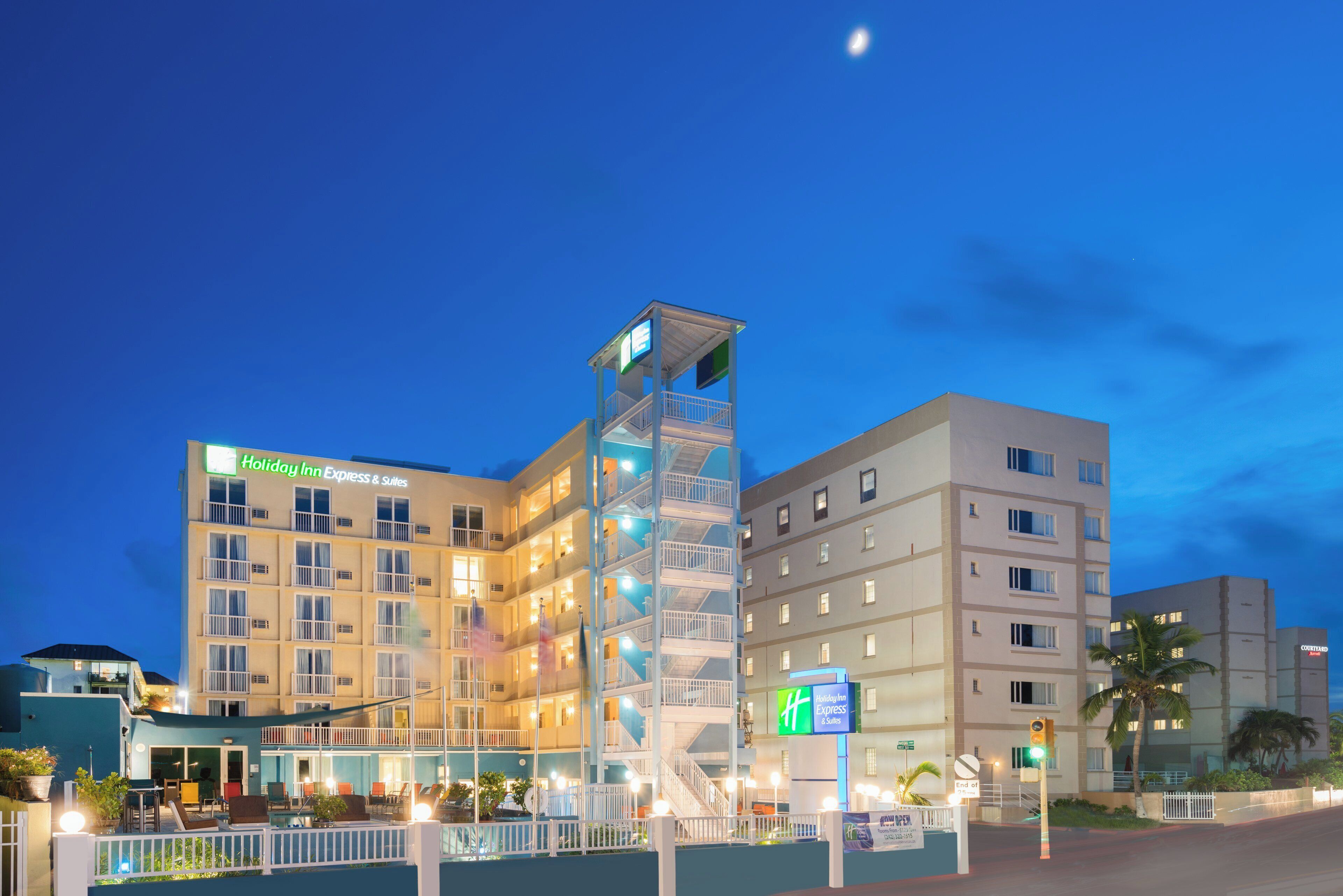 Um hotel com vários andares e uma torre vertical imponente, varandas e área de piscina.