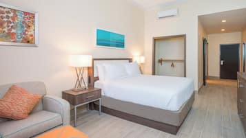 A hotel room with a bed, a nightstand with lamps, a sofa, and a painting on the wall.