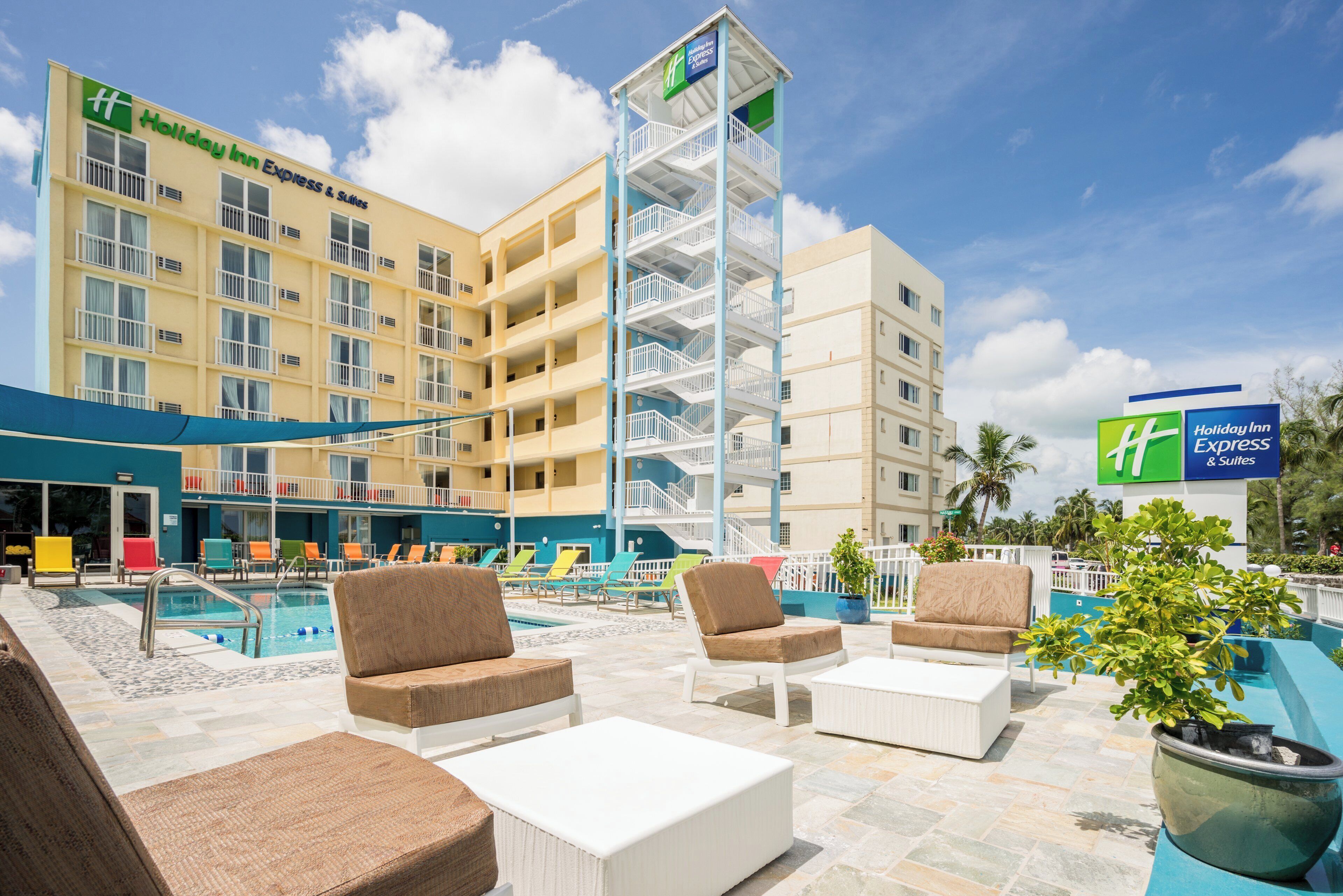 Un Holiday Inn Express & Suites con zona de piscina, mobiliario exterior y cielo despejado.