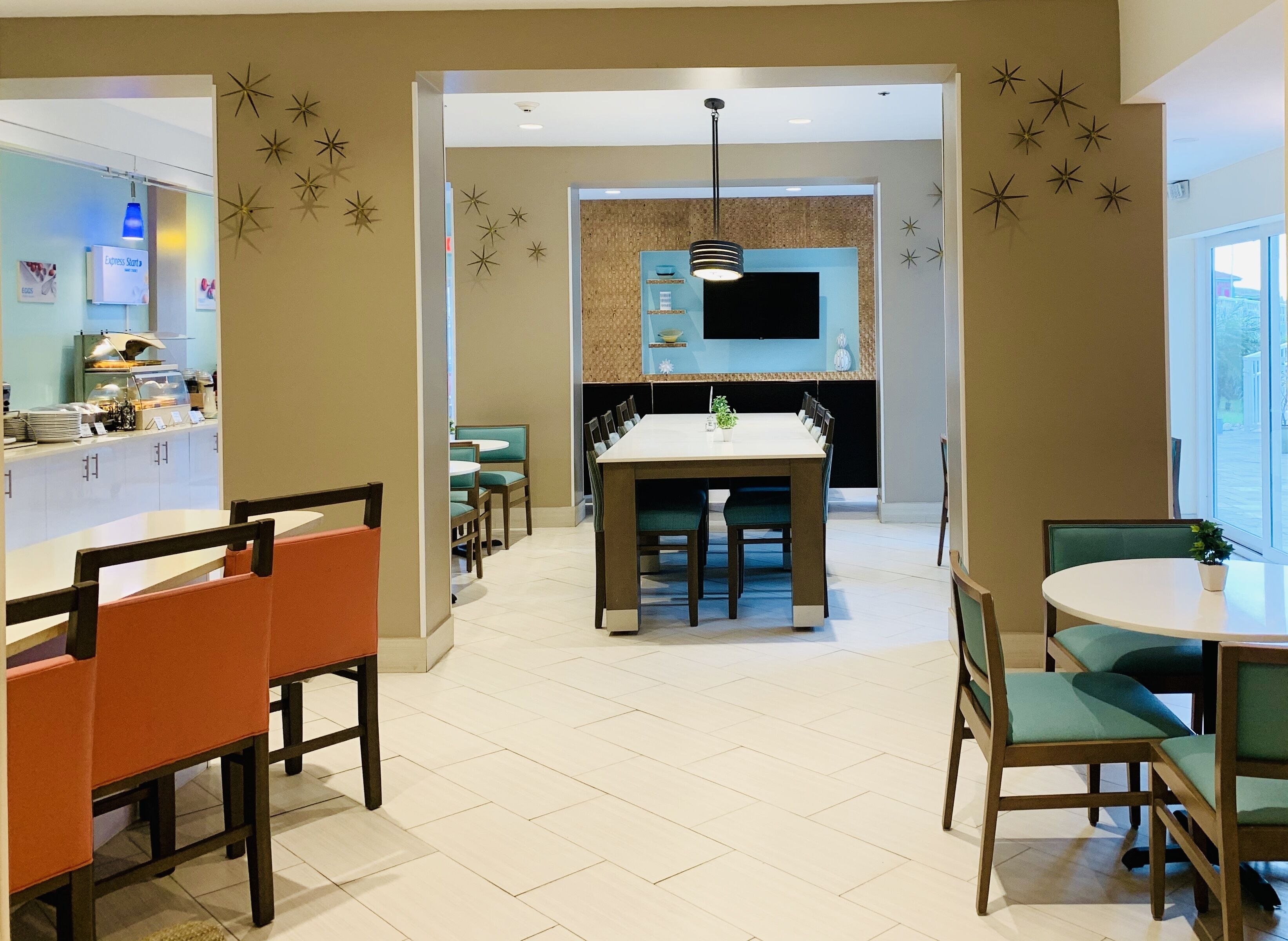A modern dining area with a central table and chairs, a kitchen in the background, and decorative star wall art.