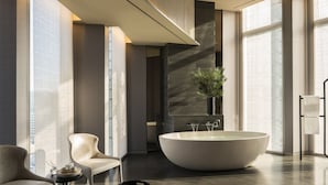 A modern bathroom with a large freestanding bathtub, two chairs, a small table with toiletries, and a potted plant. - Four Seasons Hotel Seoul (Seoul)