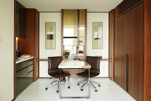 A modern kitchen with a central island, two chairs, and a large mirror above the island.