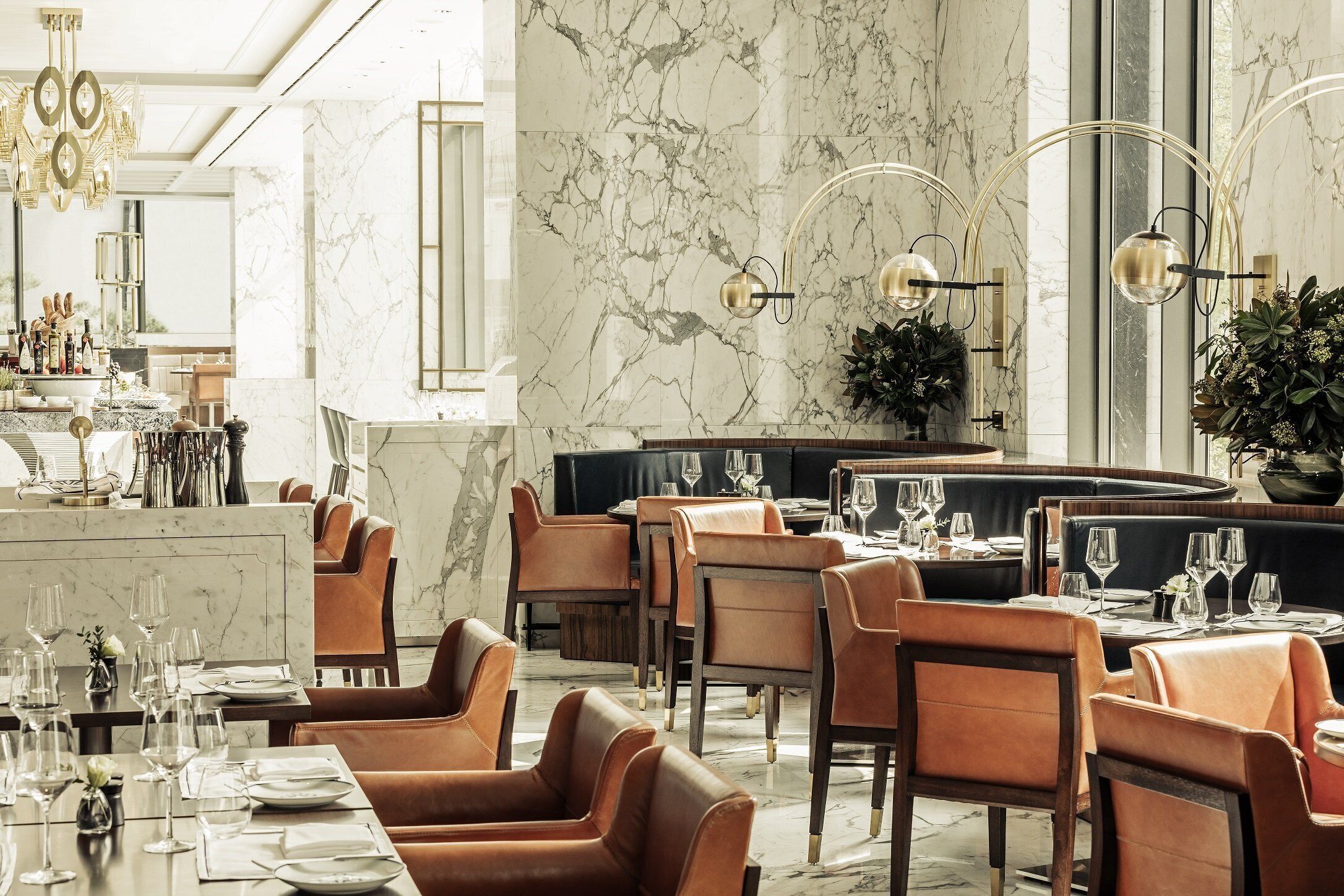 Un restaurante con paredes de mármol, sillas de cuero y una zona de bar.