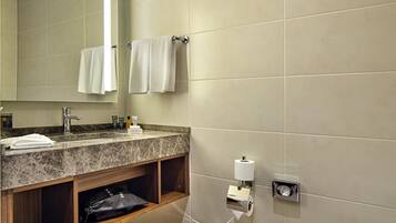 A modern bathroom with a marble sink, wooden vanity, a toilet, and a mirror.