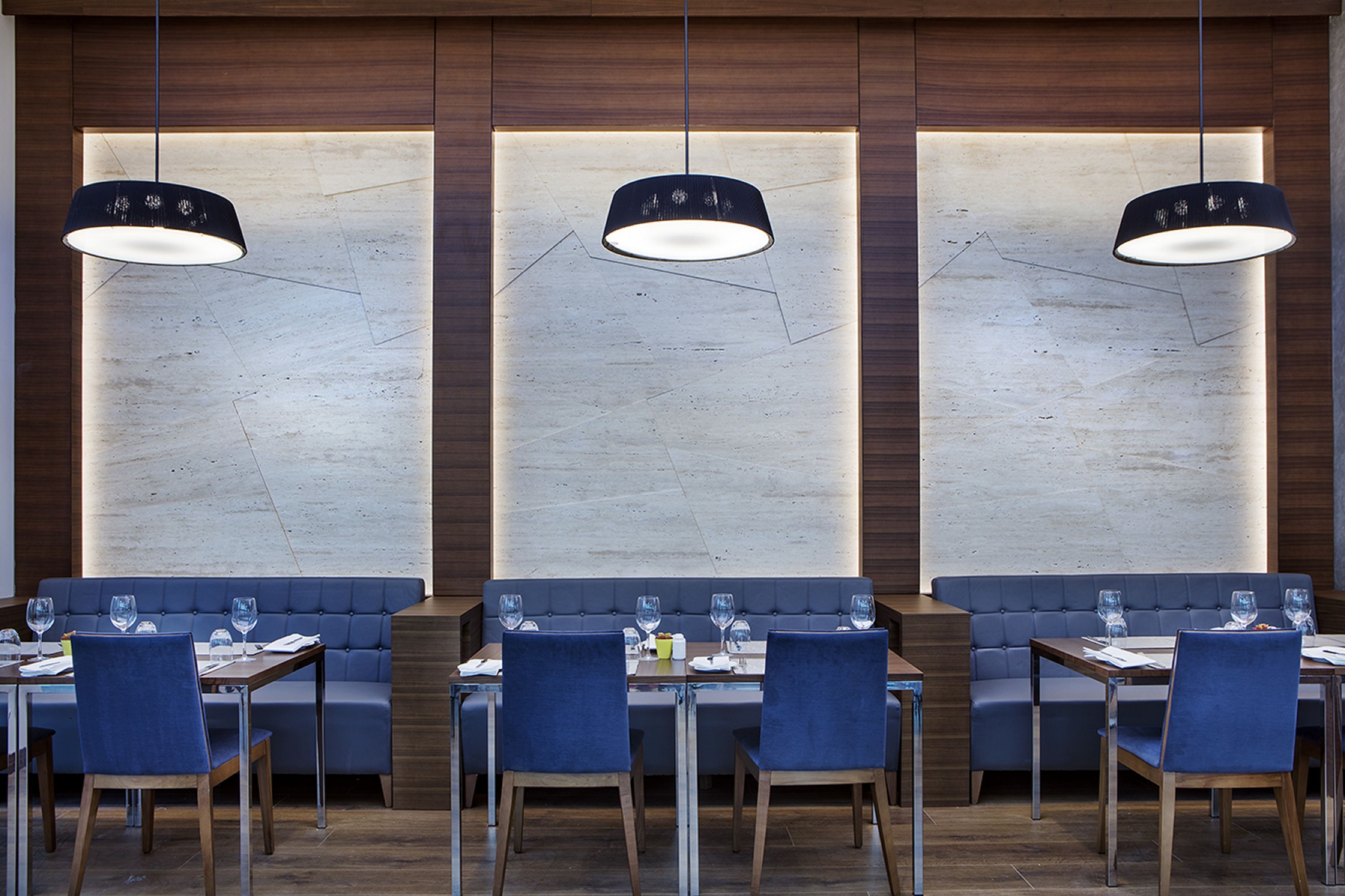 Ein modernes Restaurant mit drei Essbereichen, jeweils mit einem Tisch und Stühlen sowie Pendelleuchten.