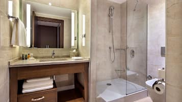 Un baño moderno con ducha envuelta en vidrio, tocador de madera con espejo y retrete.