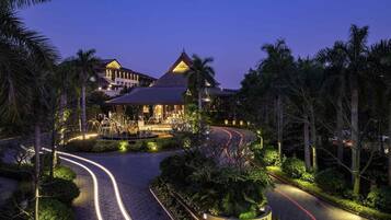 A hotel with a curved driveway, palm trees, and a sign reading 'Pullman Hotel & Residences.'