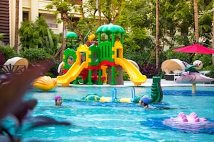 Zona de piscina con estructura acuática de juegos, que incluye toboganes y un flotador con forma de criatura marina.
