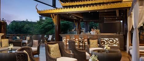 An outdoor seating area with wicker furniture and a bar.