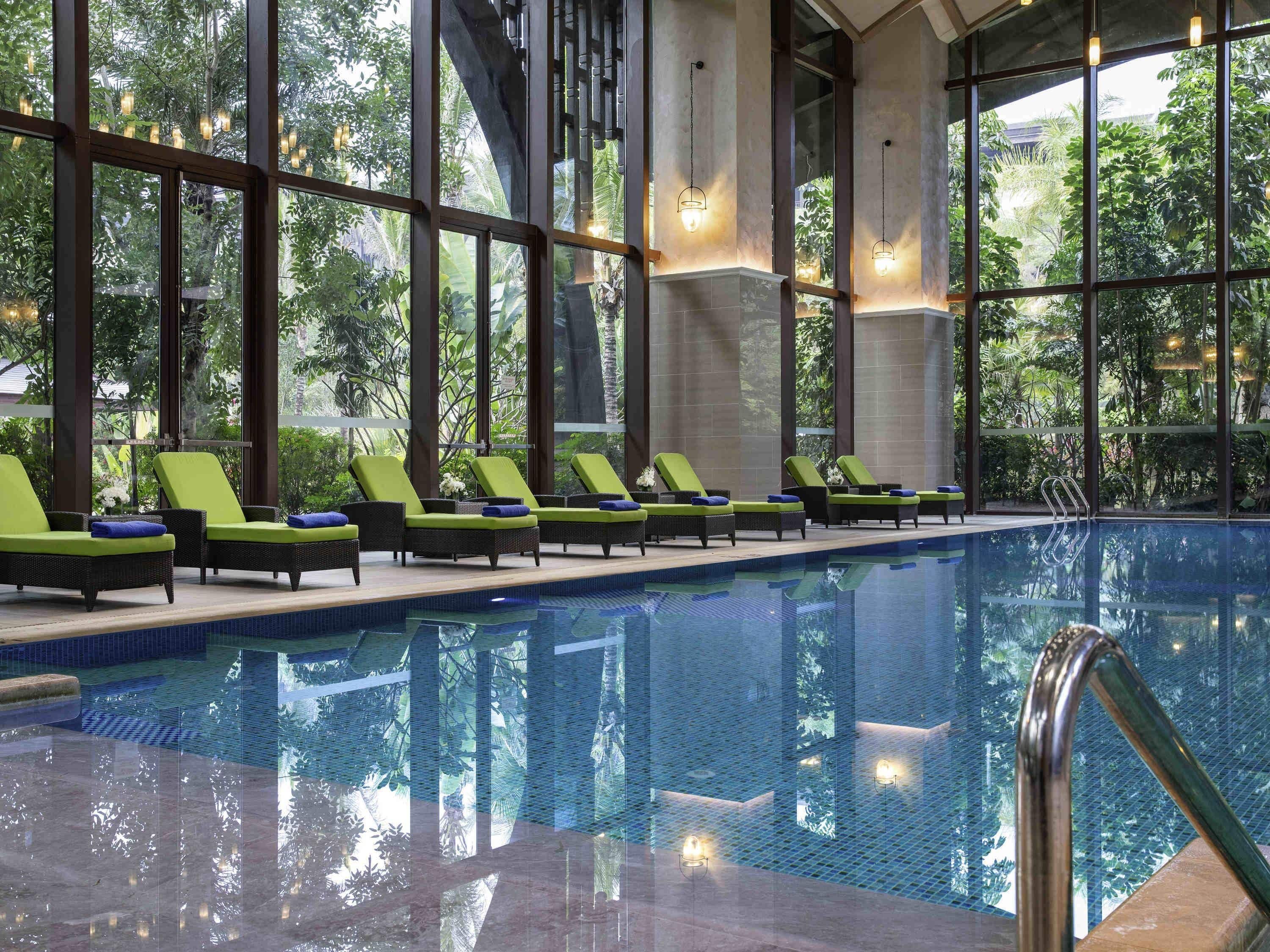 Une piscine intérieure dotée de chaises longues et de grandes fenêtres.