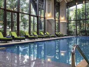 Una piscina interior con sillones de descanso y ventanas amplias.