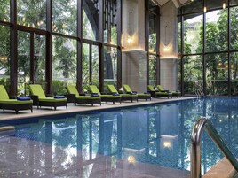 An indoor swimming pool with lounge chairs and large windows.