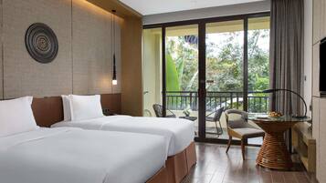 Quarto de hotel com duas camas, varanda com mesa e cadeiras, e vista para o verde lá fora.