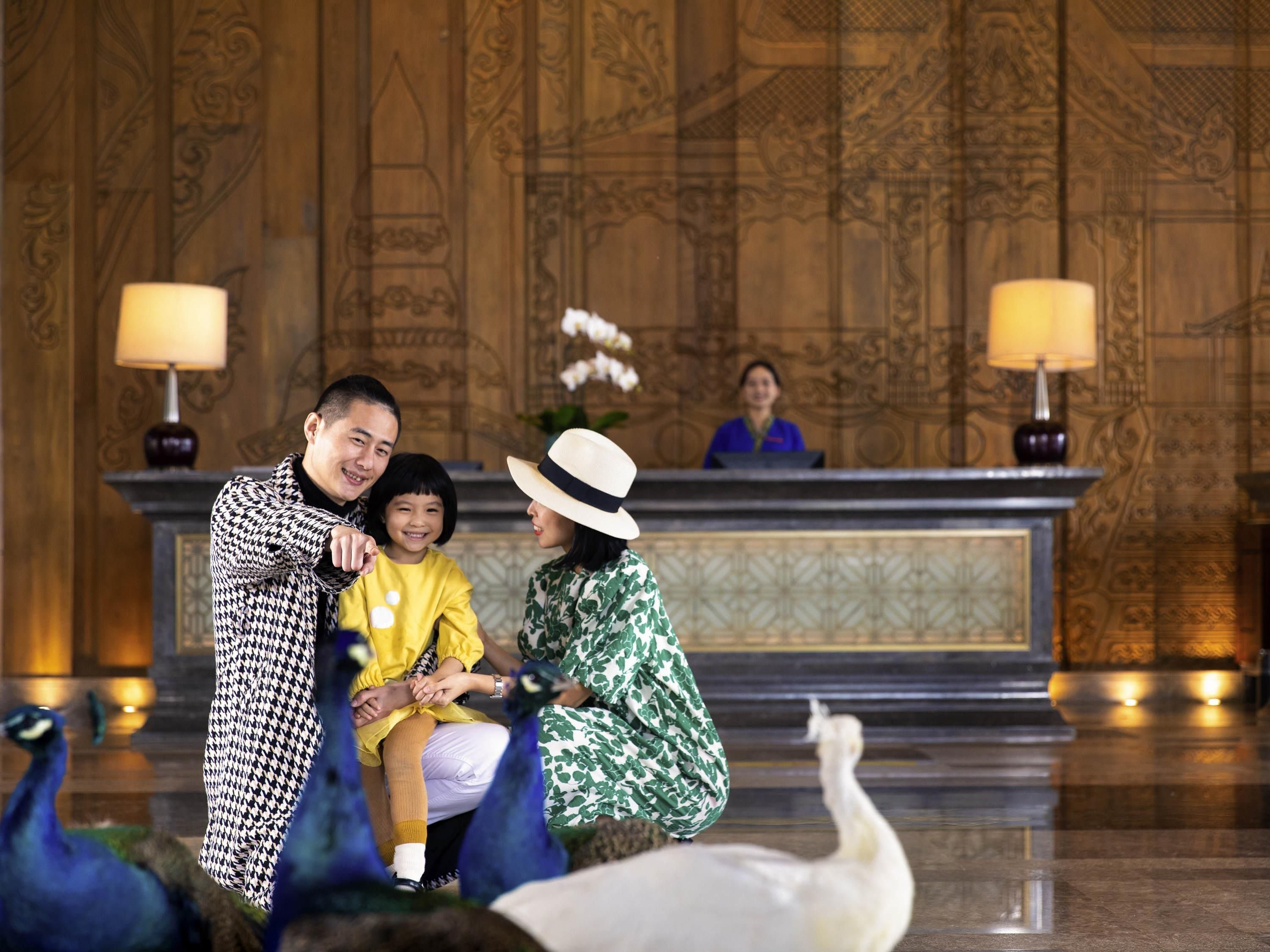 A reception area with a wooden panel wall, a reception desk, and a peacock.