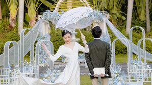 A wedding ceremony with a bride and groom under a white parasol, surrounded by white chairs and floral decorations. - Pullman Resort Xishuangbanna (Xishuangbanna Dai)