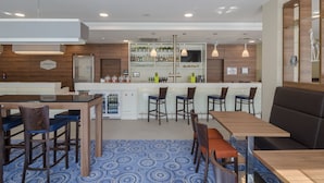 A modern hotel bar with wooden furniture, a central bar area, and a patterned carpet. - Hampton by Hilton Frankfurt City Centre (Frankfurt)