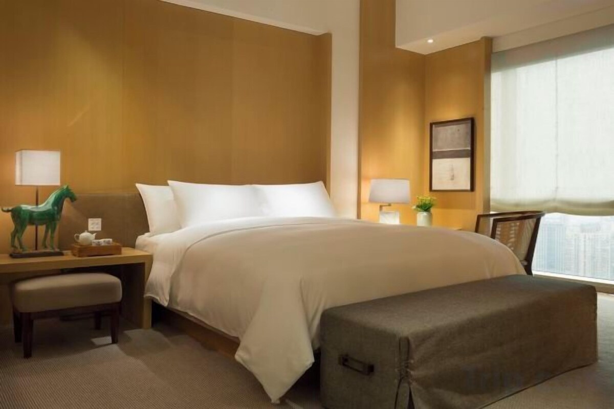 Ein Hotelzimmer mit einem Bett, Nachttischen, einem Schreibtisch und einem Fenster.