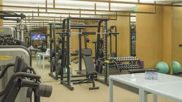 A gym with various exercise equipment, a white table, and exercise balls.