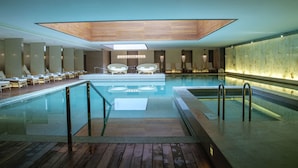 A modern indoor pool with clear glass walls, wooden deck, and lounge chairs. - Grand Hyatt Chengdu (Chengdu)