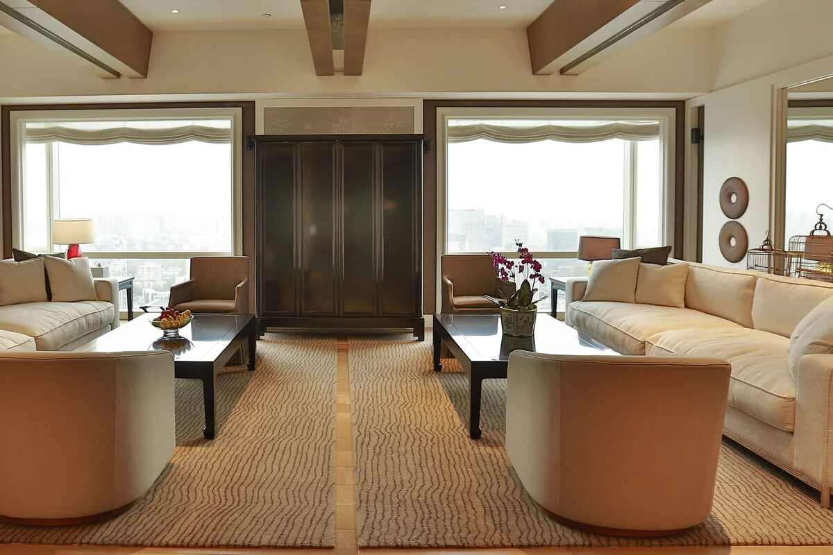Ein modernes Wohnzimmer mit zwei Sofas, einem Couchtisch und einem großen Fenster mit Blick auf die Stadt.