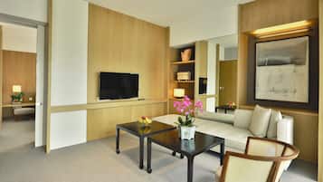 A modern hotel room with a flat-screen TV, a sofa, a coffee table, and a dining table.