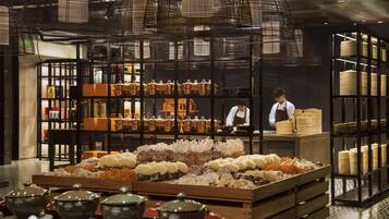 A restaurant interior with a chef at the counter, wooden crates with food items, and shelves with kitchenware.