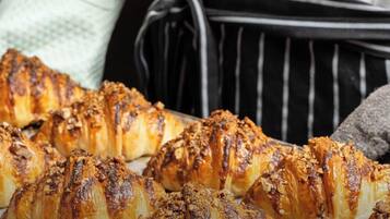 A tray of croissants with a golden-brown crust, likely freshly baked, with a sprinkling of nuts on top.