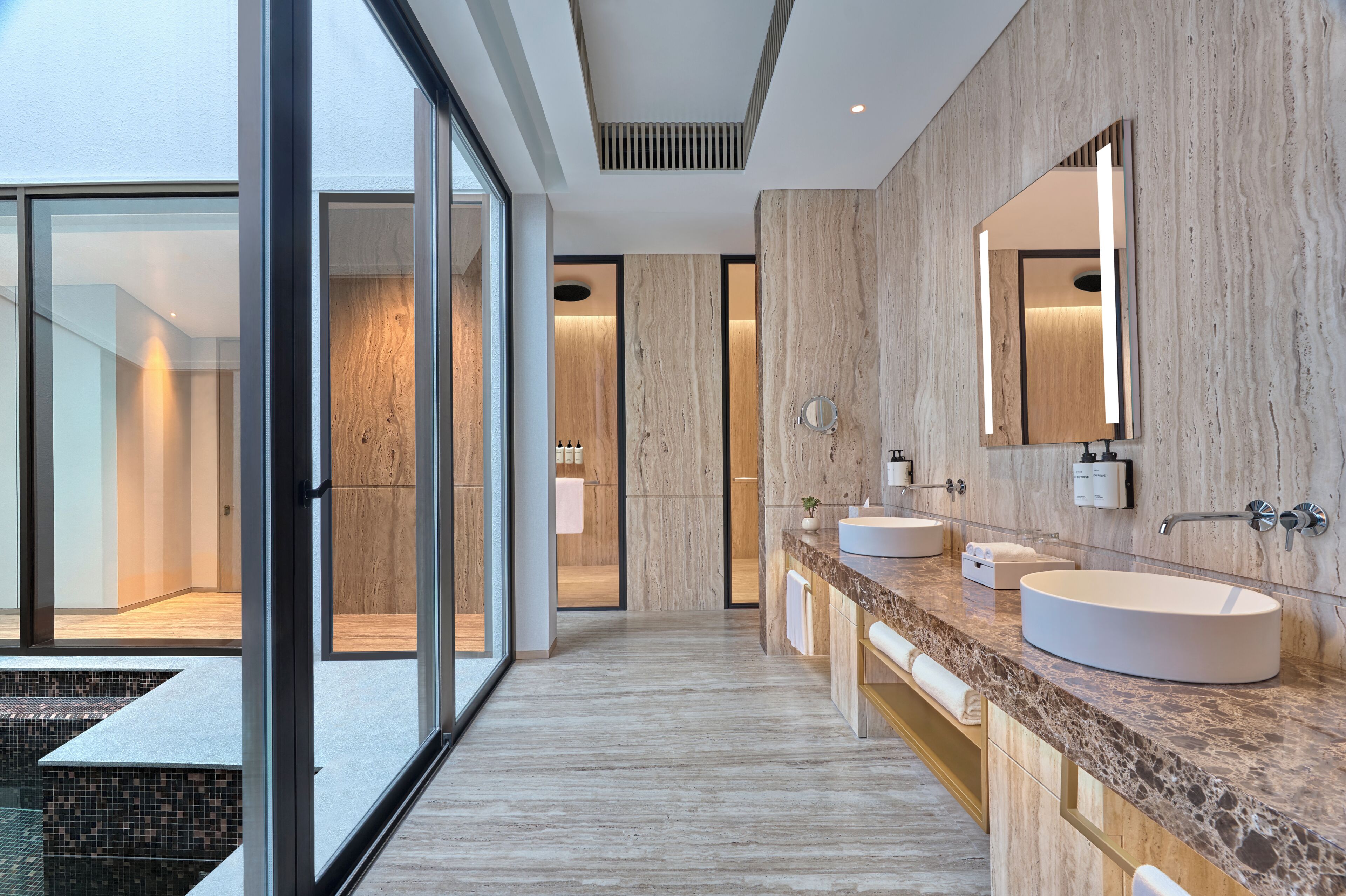 A modern bathroom with large mirrors, two sinks, and a glass-enclosed shower area.