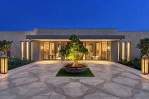 A modern building with a large entrance, a central tree, and a paved courtyard. - InterContinental Chennai Mahabalipuram Resort by IHG (Tirupporur)