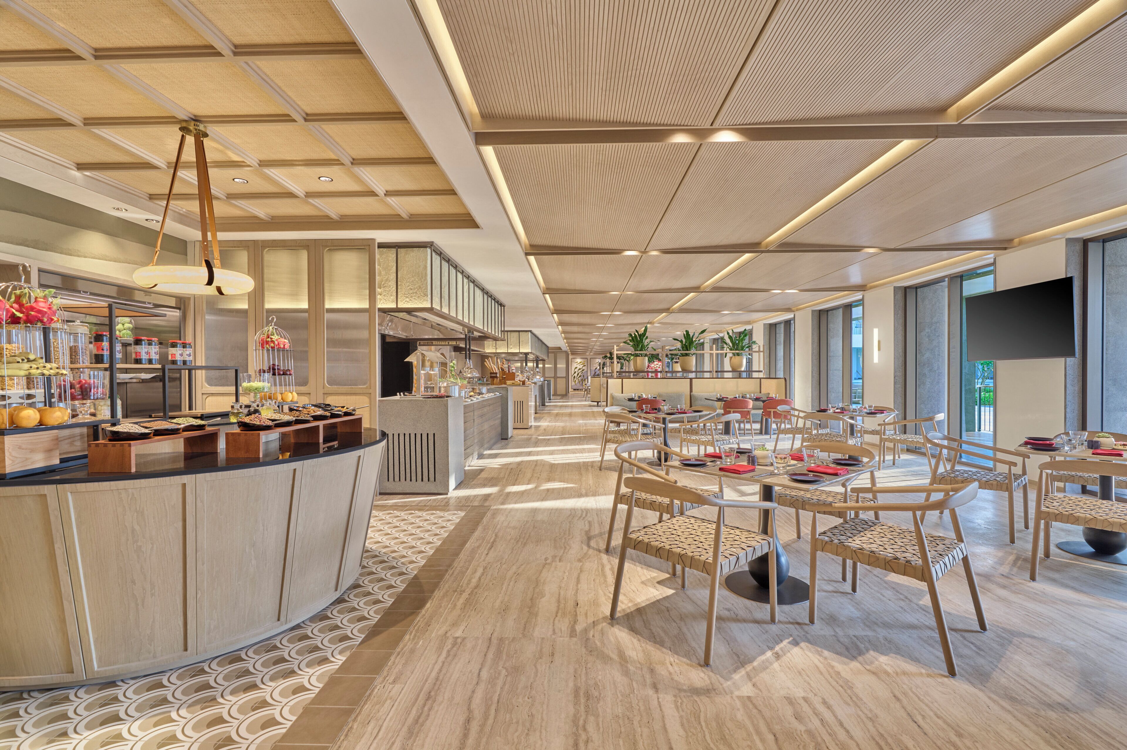 A modern hotel lobby with a central bar area, seating arrangements, and a patterned floor.