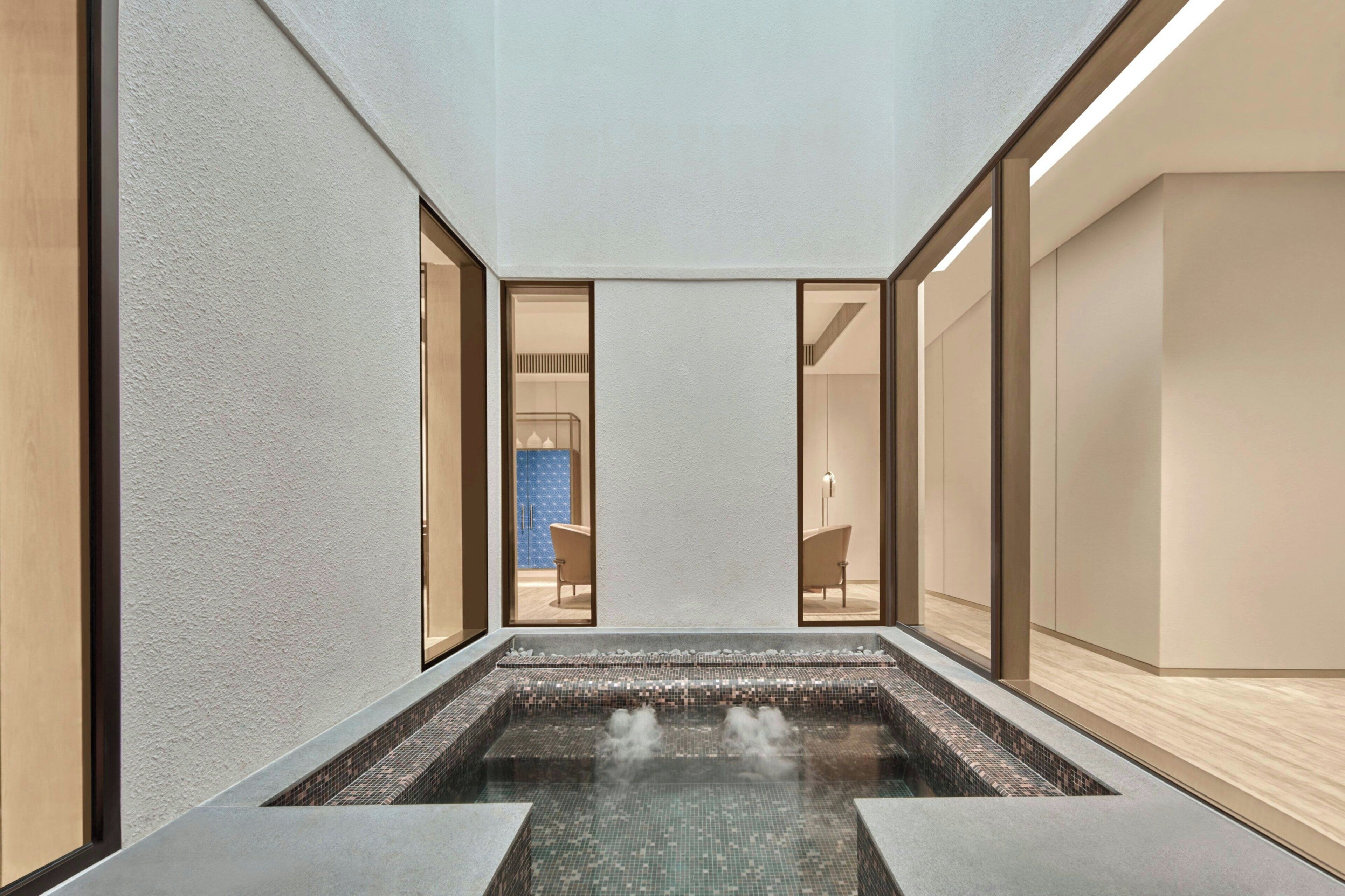 A modern spa with a central hot tub, glass walls, and a minimalist design.