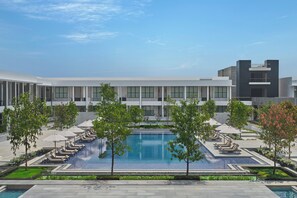 A modern hotel with a central swimming pool, sun loungers, and a clear sky. - InterContinental Chennai Mahabalipuram Resort by IHG (Tirupporur)