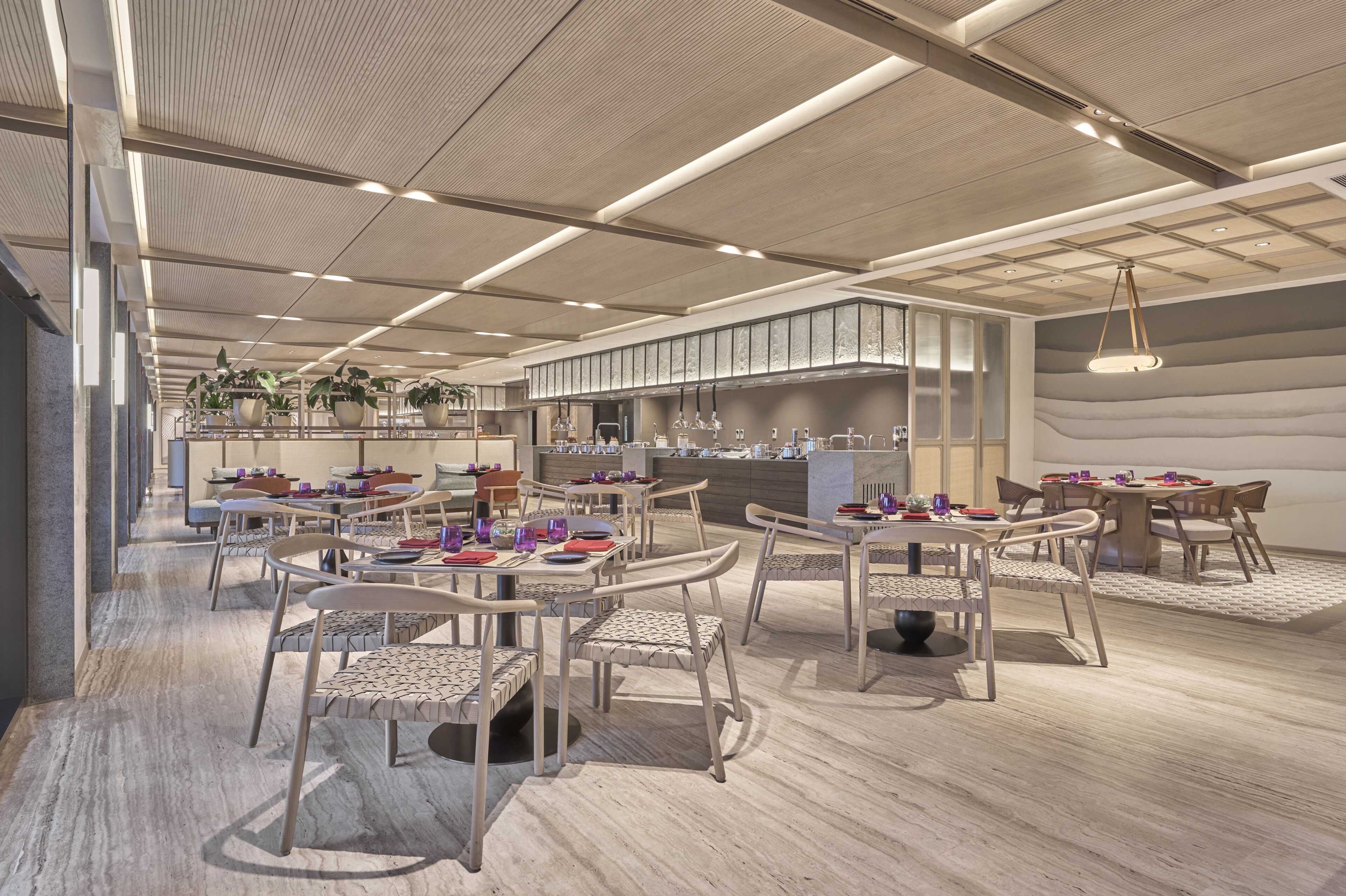 A modern restaurant interior with high ceilings, pendant lighting, and a central bar area.