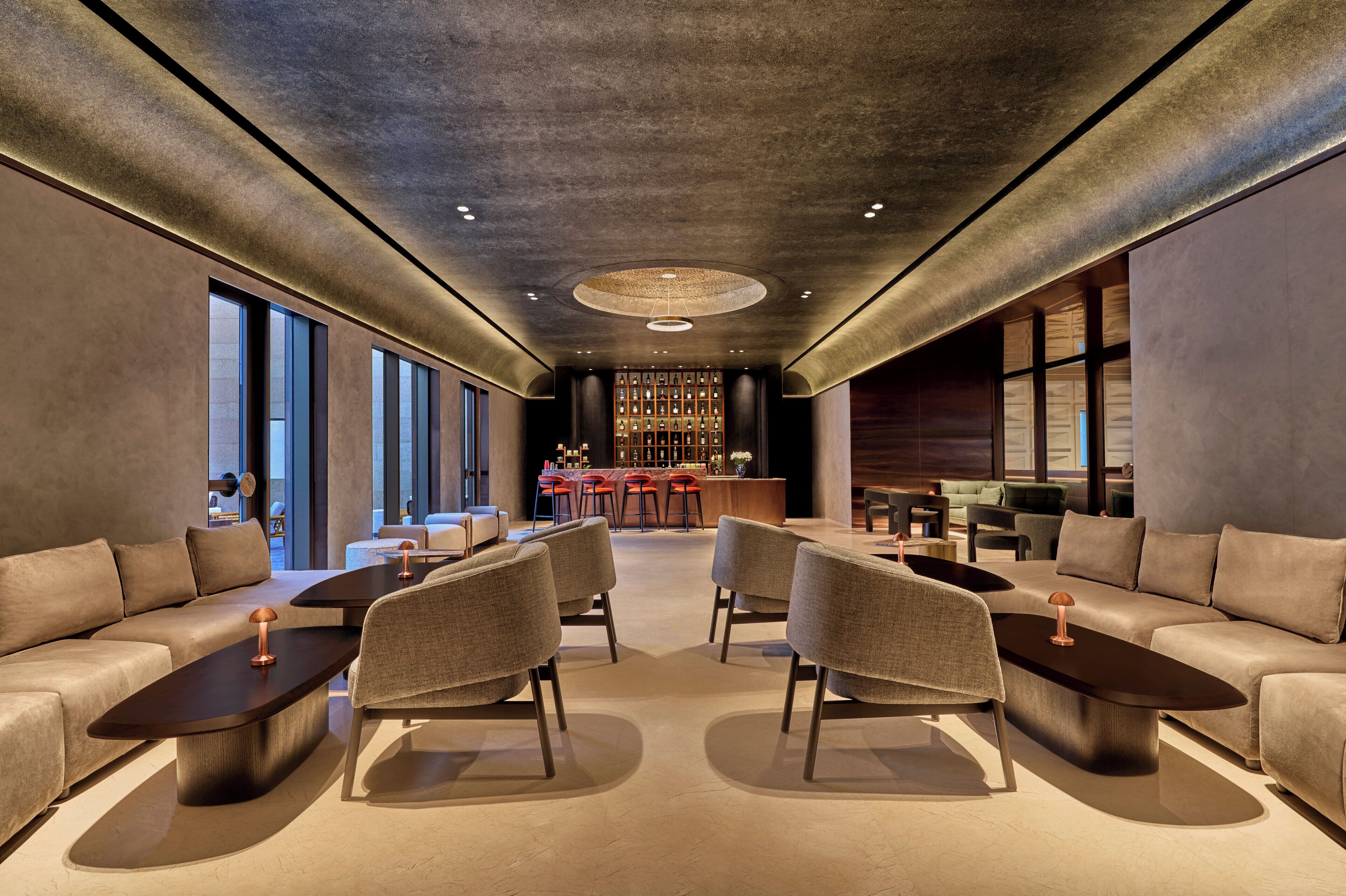 A modern lounge area with sofas, armchairs, and a bar.
