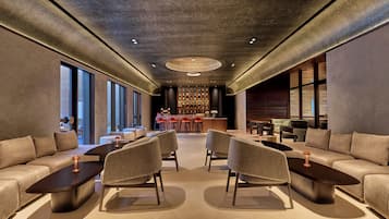 A modern lounge area with sofas, armchairs, and a bar.