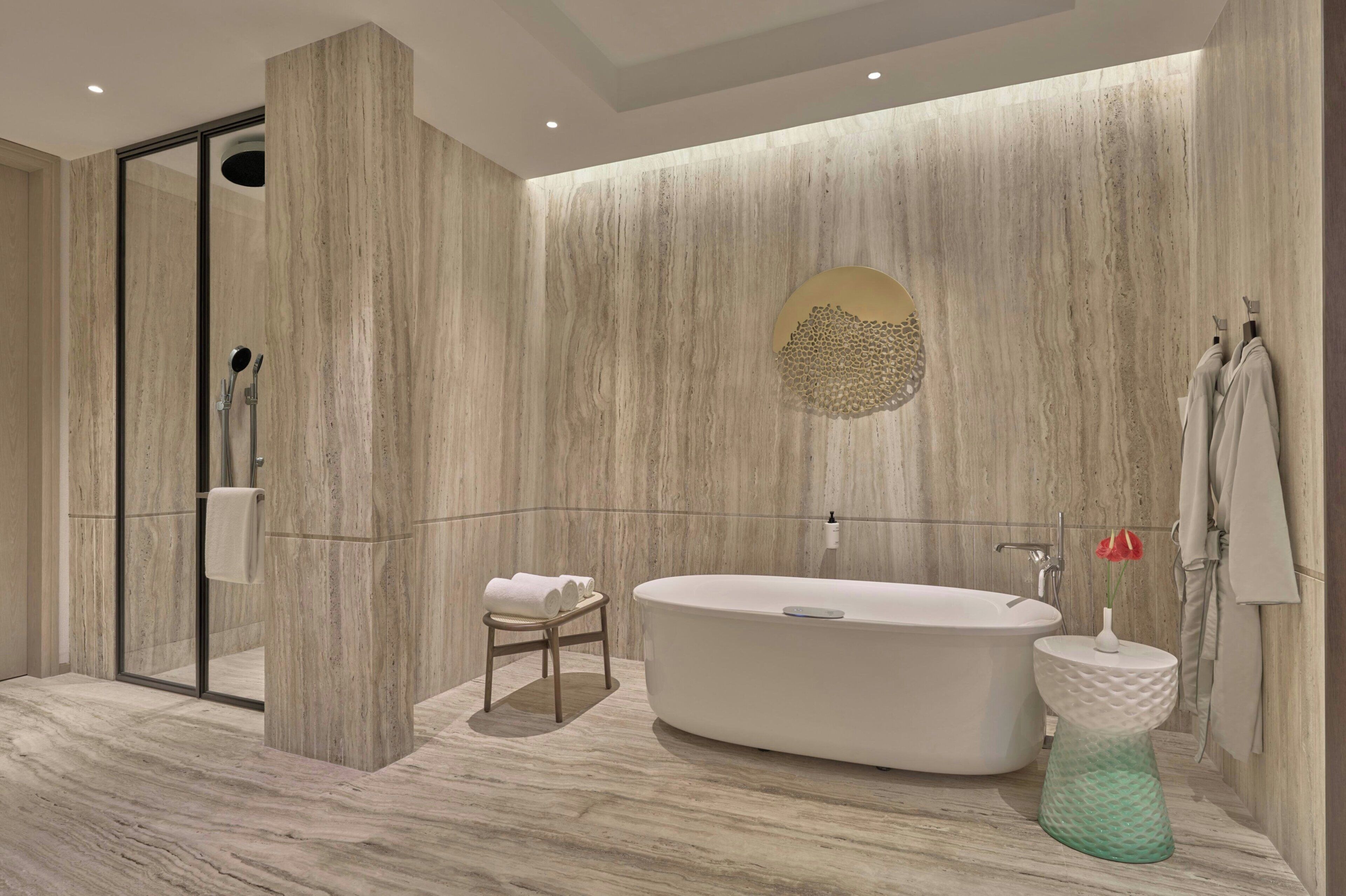 Un baño moderno con una bañera independiente, cabina de ducha con mampara de vidrio y un perchero con toallas.