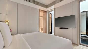 A hotel room with a large bed, a flat-screen TV mounted on the wall, and a view of the outdoors through a sliding door.