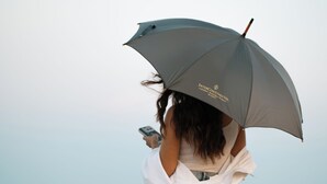 A person holding an umbrella, standing by the ocean.