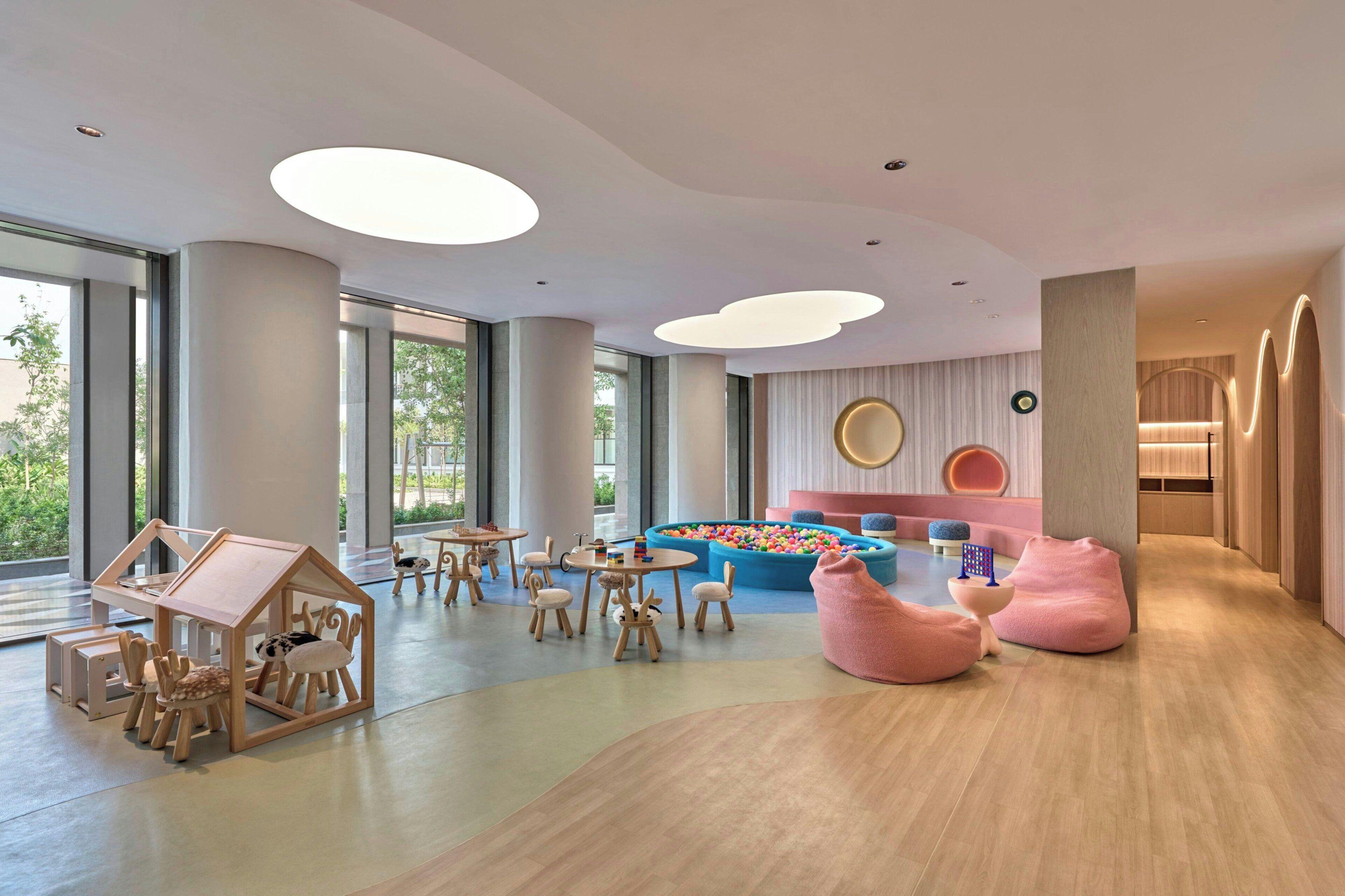 A spacious children's play area with a playhouse, tables, chairs, and a ball pit.