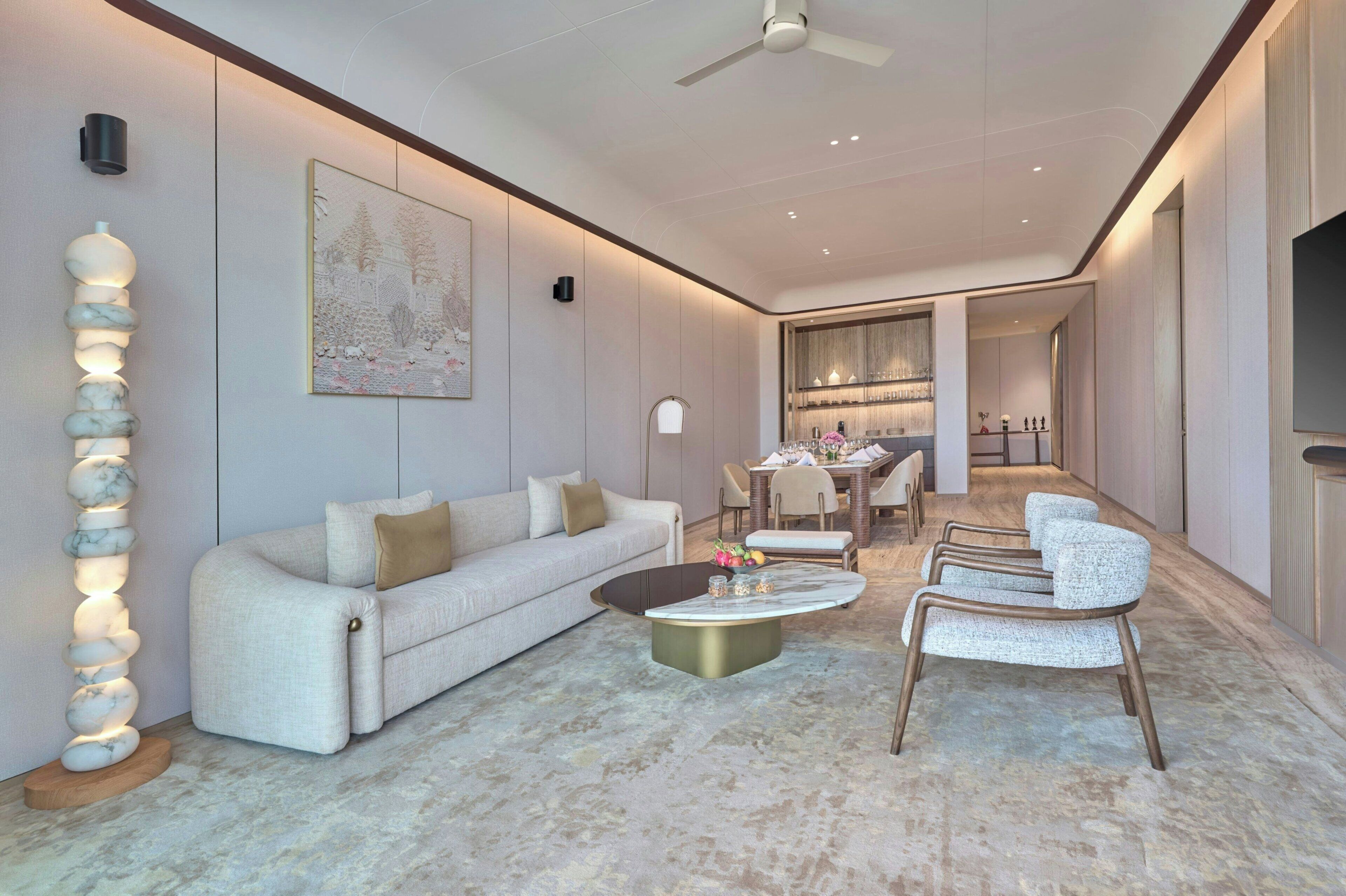 Un salon moderne comprenant un canapé, une table basse et des fauteuils, un coin repas avec une table et des chaises, et un ventilateur de plafond.